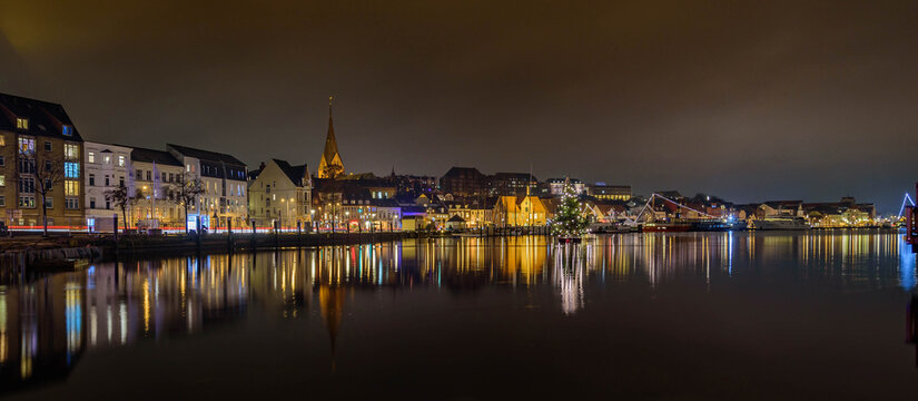 Panorama view of of festive lighting and Christmas romantic atmosphere in the Flensburg at night. Nighttime view of Flensburg F&ouml;rde at Christmas time. Maritime Christmas city.