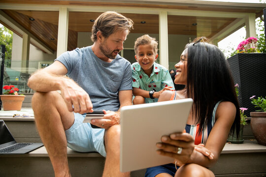 Family Making Online Purchase With Digital Tablet On Steps