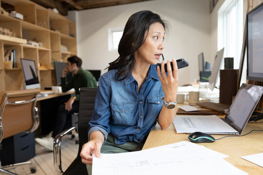 Designer in architecture firm talking through plans on phone