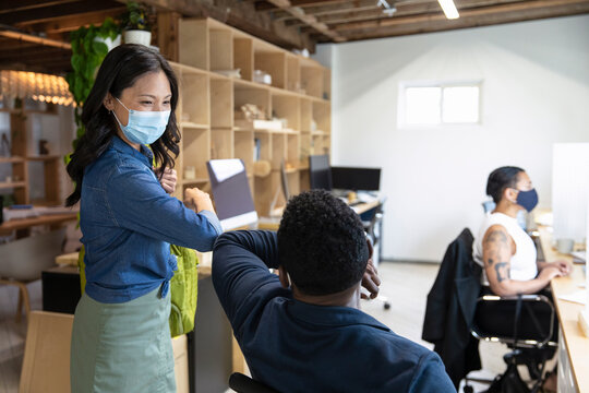 Coworkers In Facemask Elbow Bumping In Workspace