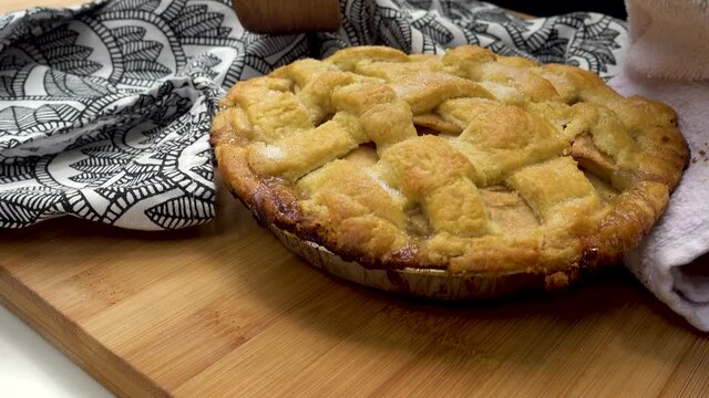 Freshly baked apple pie put down on table. Hand-made traditional apple pastry fresh out of the oven placed on wooden counter.