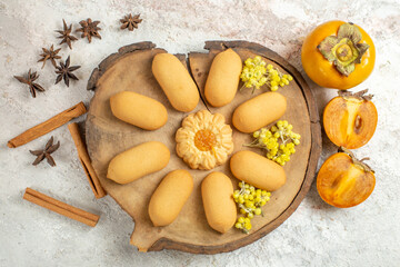 cookies on wooden platter and palms and cinnamon sticks and anises on white marble background