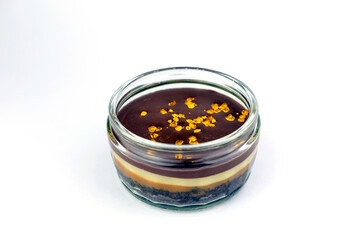 Luxurious cheese cake dessert in a glass jar with edible gold flakes on top of it. Isolated on white.