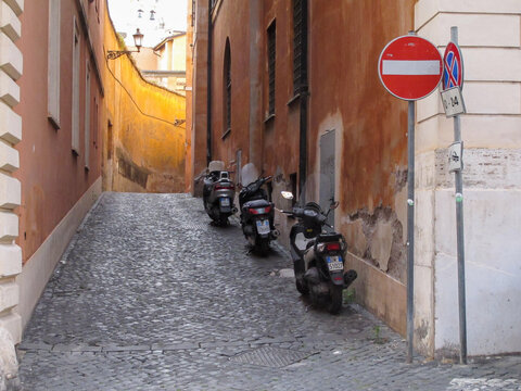 A row of 3 motorbikes parked in a charming Roman alleyway in Rome, Italy.  Image has copy space.