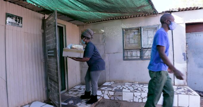 Black African man delivering food parcels to the poor and hungry who are badly affected by Covid-19 Coronavirus pandemic in South Africa