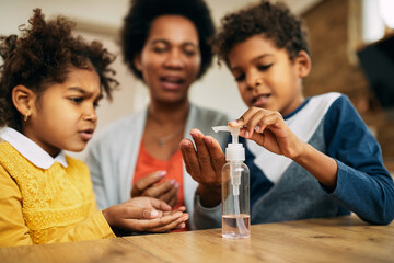 Close-up of black family disinfecting their hands at home.