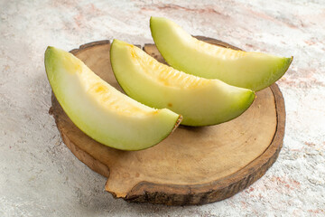 three slices of melon on wooden platter on marble background