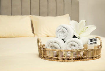 Rolled clean towels and shampoo bottles on bed. Space for text