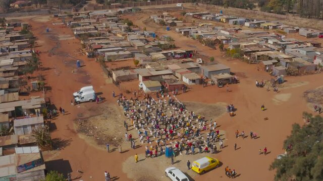 AFRICA,SOUTH AFRICA,CIRCA 2020.  Aerial view of Black African people social distancing receiving food parcels in a poverty stricken informal settlement during lockdown, Covid-19 Coronavirus pandemic