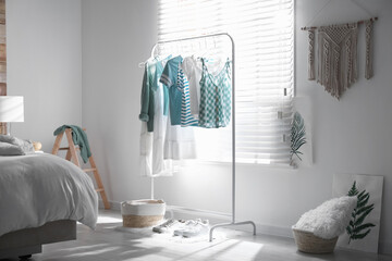 Stylish bedroom interior with clothing rack and large window