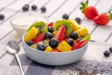 Healthy food concept photo. Fresh fruits and berries salad with yogurt and chia on white background. Selective focus.