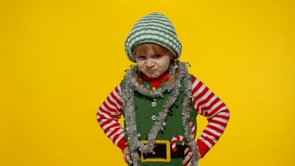 Displeased little blonde kid teen teenager girl in Christmas elf Santa helper costume isolated on...