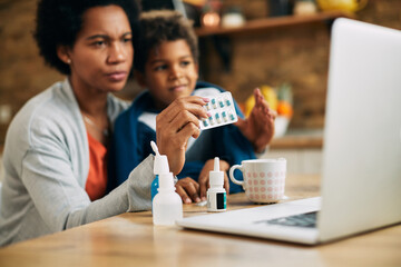 Close-up of black mother consulting with a doctor online about medicine for her son.