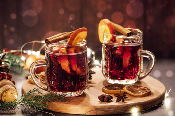 Hot mulled wine with spices in glass cup on wooden background. Traditional Christmas warming drink.