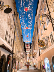 Fototapeta premium Salzburg old town with famous Getreidegasse decorated with Christmas lights during blue hour at dusk in winter, Salzburg Land, Austria