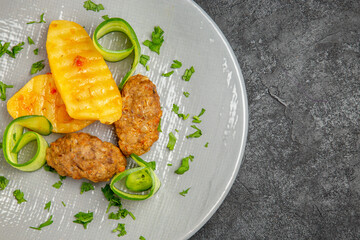 Half shot of tasty dinner with cutlet meal along with potatoes on a white plate on dark table