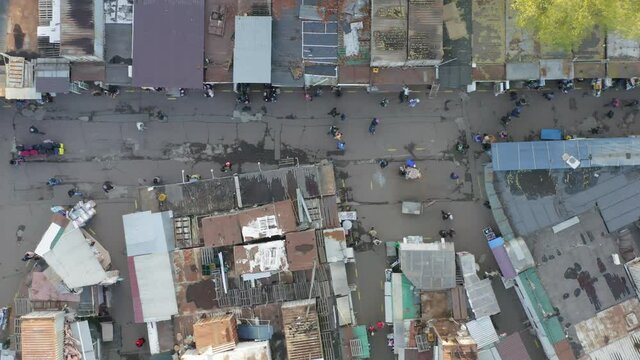Aerial top-down view of a bazaar in a slum with people between the rows.
