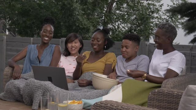 Family Watching Movie On Laptop In Backyard