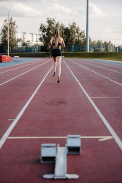 Female jogger starting run on stadium track