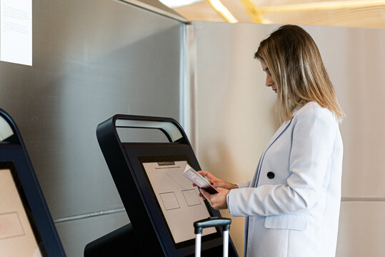 woman using the check-in machine at the airport getting the boarding pass.