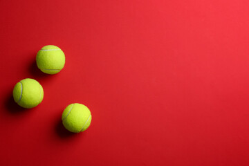 Tennis balls on red background, flat lay. Space for text
