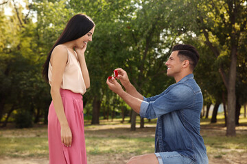 Fototapeta na wymiar Man with engagement ring making proposal to his girlfriend in park