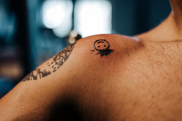 Crop man shoulder with smiling face tattoo on shoulder