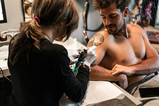 tattoo artist woman making tattoo to man