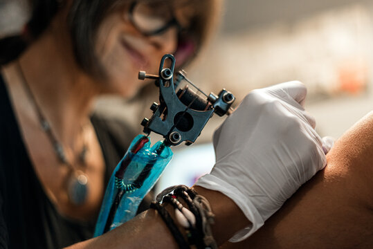 tattoo artist woman making tattoo for man