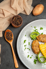 Vertical view of homemade cutlet meal along with potatoes with different spices on dark table