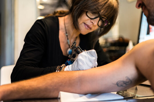 Female tattooist working with male client