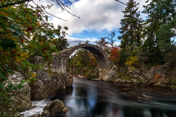 old stone bridge over red river in scotland at autumn
