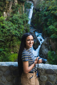 A girl with a camera in her hand in front of the waterfall