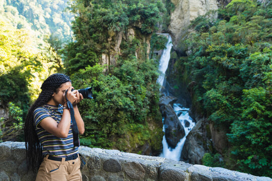 Girl with a camera taking pictures in the waterfall