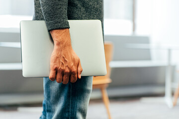 Unrecognizable businessman with laptop at office