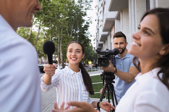 Professional journalist and operator with video camera taking interview outdoors