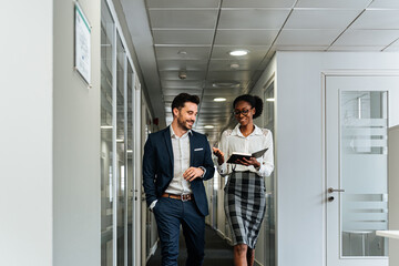 Colleagues in formal wear discussing business project in hall of office