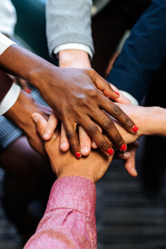 Faceless colleagues joining hands at work space