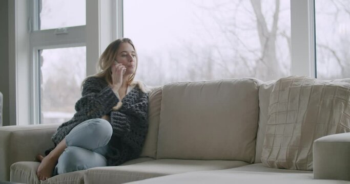 Woman Talking Calling on Cell Mobile Phone Smartphone gets Bad Sad Concerning Tragic News from Friend Family Doctor in Living Room on Couch