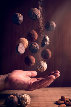 male hand open palm up recibing falling chocolate truffles candies