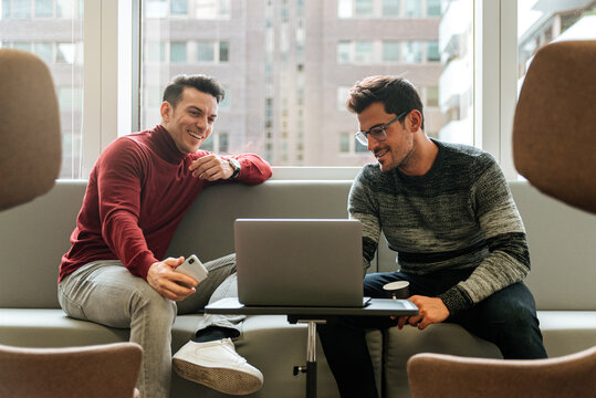 Confident man at laptop working with partner in office
