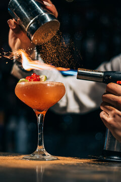 Bartender spilling and burning spices over cocktail