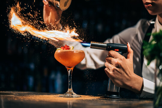 Bartender spilling and burning spices over cocktail