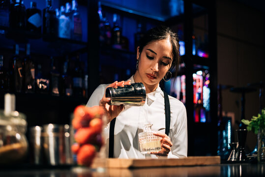 Female Mixologist Pouring Liquor In Bottle