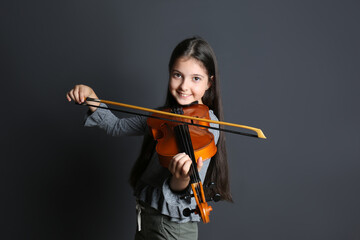 Preteen girl playing violin on black background