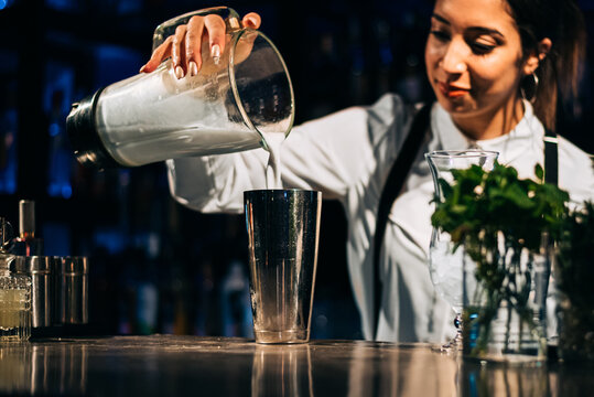Female barkeeper pouring dairy into shaker