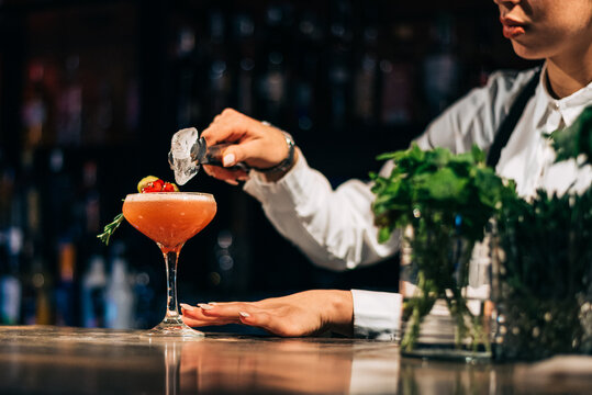 Blurred bartender decorating cocktail in pub