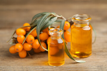 Natural sea buckthorn oil and fresh berries on wooden table