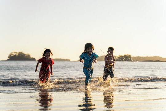 Group of cute panamanian kids running and having fun together in the beach