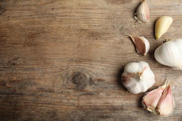Fresh organic garlic on wooden table, flat lay. Space for text